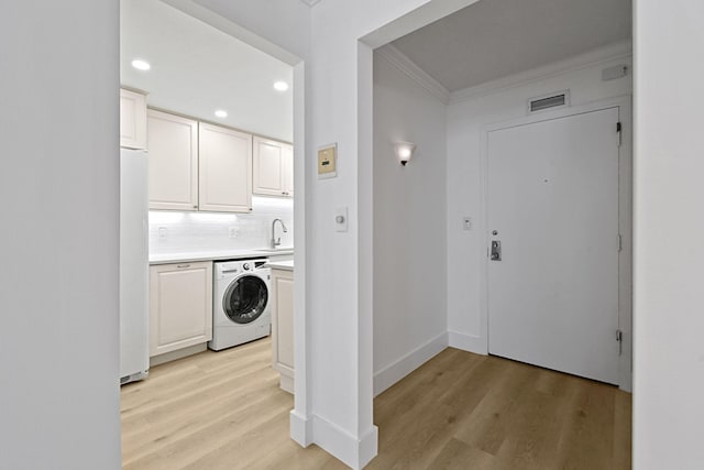 washroom featuring cabinets, washer / dryer, light wood-type flooring, and crown molding