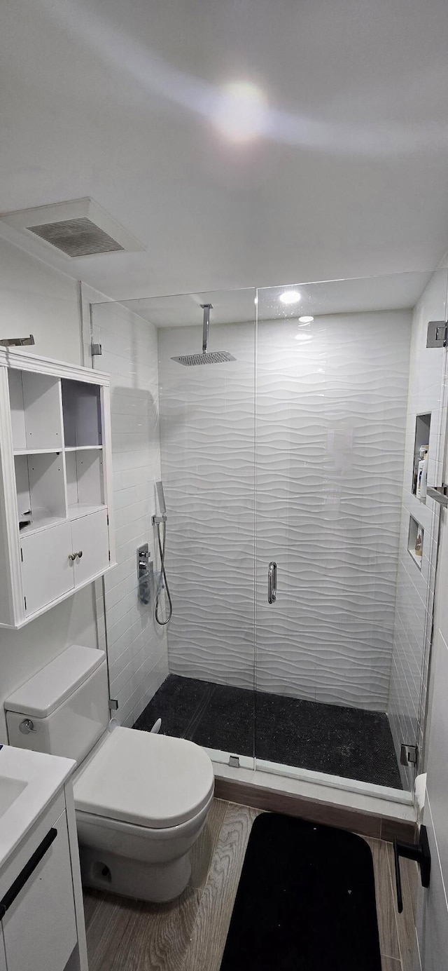 bathroom featuring vanity, toilet, and an enclosed shower