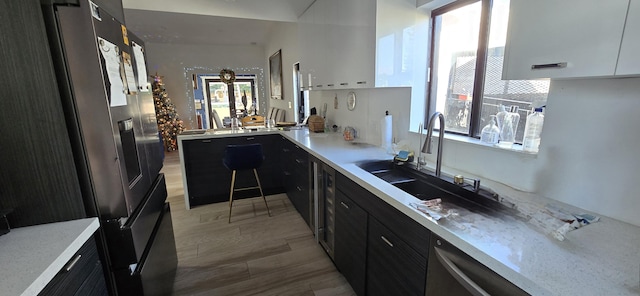 kitchen featuring white cabinetry, light hardwood / wood-style flooring, stainless steel refrigerator with ice dispenser, and sink