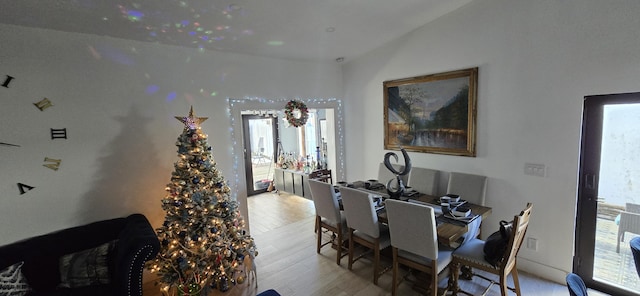 dining area with light hardwood / wood-style floors, vaulted ceiling, and a wealth of natural light