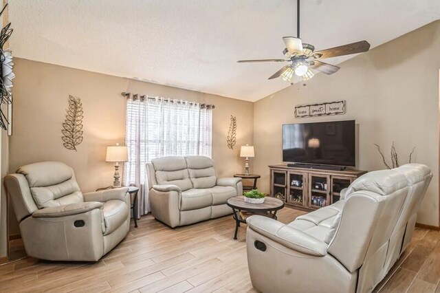 living room with ceiling fan, light hardwood / wood-style floors, and lofted ceiling