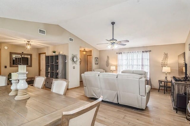 dining space featuring ceiling fan, vaulted ceiling, and light wood-type flooring