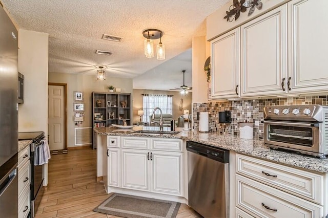 kitchen featuring ceiling fan, sink, stainless steel appliances, kitchen peninsula, and light hardwood / wood-style floors