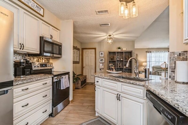 kitchen featuring appliances with stainless steel finishes, a textured ceiling, light hardwood / wood-style flooring, and sink