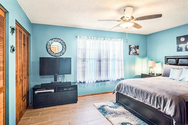 bedroom with a textured ceiling, light hardwood / wood-style floors, and ceiling fan