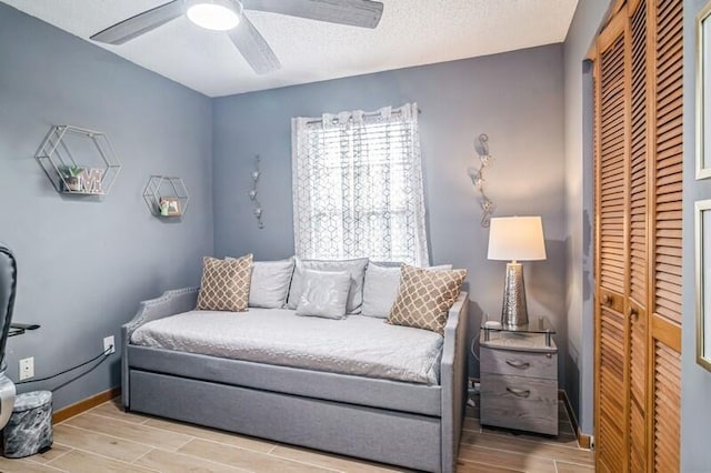 interior space with ceiling fan, light wood-type flooring, a textured ceiling, and a closet