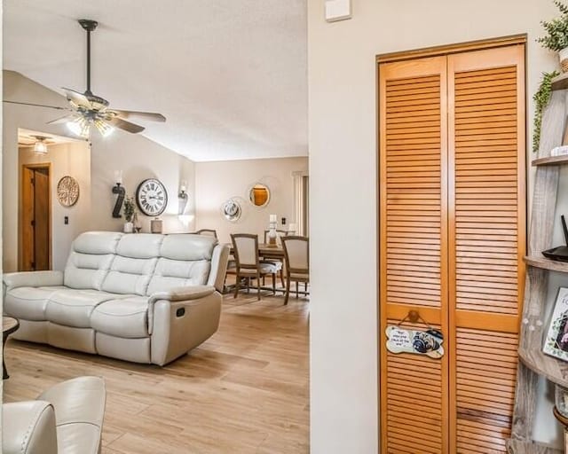 living room featuring ceiling fan, vaulted ceiling, and light wood-type flooring