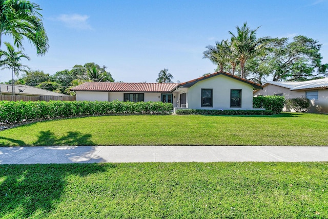 view of front of property featuring stucco siding, a front yard, and a tile roof