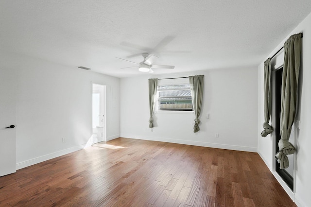 empty room featuring wood finished floors, baseboards, visible vents, ceiling fan, and a textured ceiling