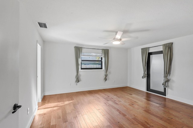 spare room with light wood-type flooring, visible vents, baseboards, and ceiling fan