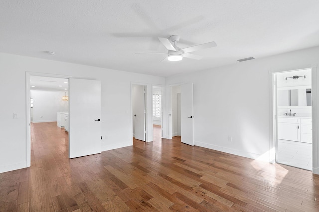 unfurnished bedroom featuring connected bathroom, hardwood / wood-style flooring, and ceiling fan