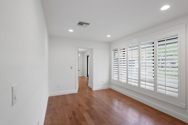 spare room featuring recessed lighting, wood finished floors, visible vents, and baseboards