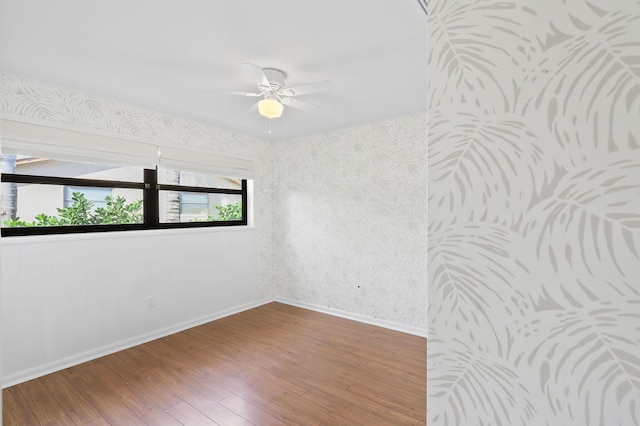 empty room with ceiling fan, wallpapered walls, baseboards, and hardwood / wood-style floors