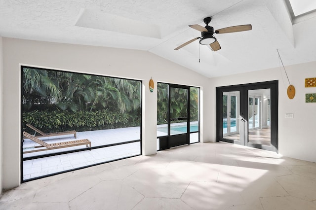 empty room with french doors, a textured ceiling, a ceiling fan, and vaulted ceiling