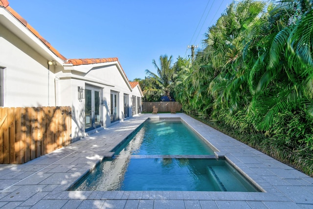 view of pool with french doors, a patio, a fenced backyard, and a pool with connected hot tub