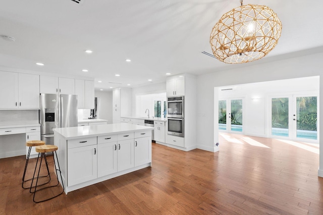 kitchen featuring a kitchen island, light countertops, light wood-style flooring, appliances with stainless steel finishes, and french doors