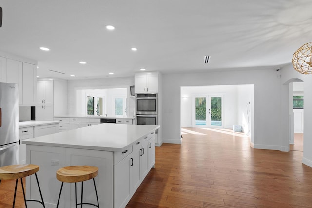 kitchen featuring appliances with stainless steel finishes, light wood-type flooring, a kitchen breakfast bar, a center island, and white cabinetry