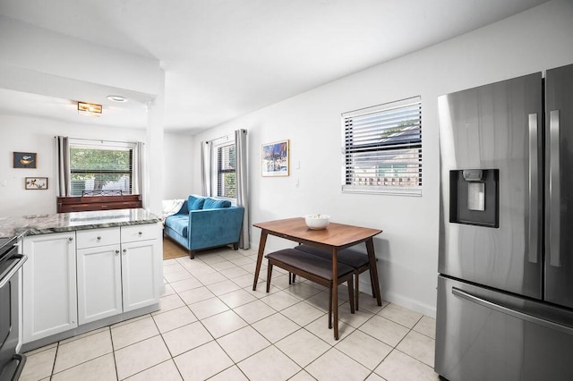 kitchen featuring white cabinetry, light stone countertops, stainless steel fridge with ice dispenser, and light tile patterned floors