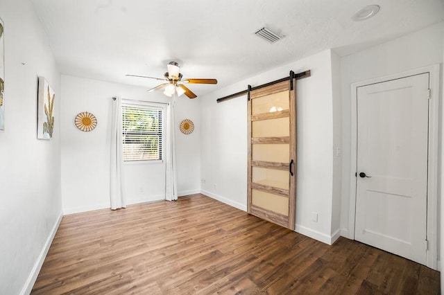 611 Monceaux Rd, West Palm Beach, FL 33405 - unfurnished bedroom with a barn door, wood finished floors, baseboards, and connected bathroom