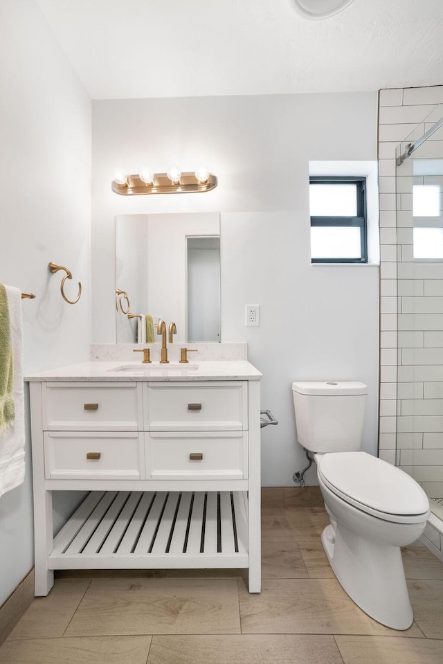 bathroom featuring tiled shower, vanity, and toilet