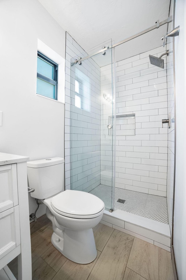 bathroom featuring walk in shower, vanity, wood-type flooring, and toilet