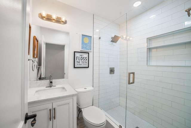 bathroom featuring vanity, a shower with shower door, and toilet