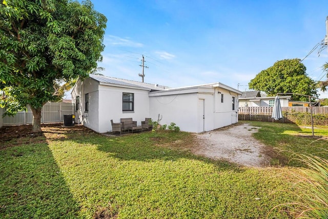 611 Monceaux Rd, West Palm Beach, FL 33405 - rear view of house featuring stucco siding, metal roof, and central AC unit