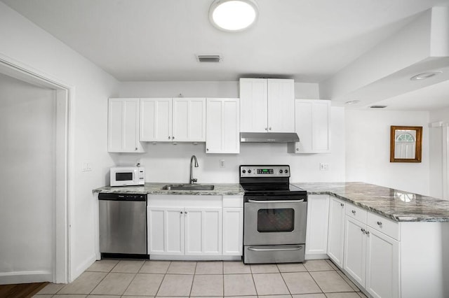 611 Monceaux Rd, West Palm Beach, FL 33405 - kitchen with stainless steel appliances, under cabinet range hood, a sink, a peninsula, and white cabinetry
