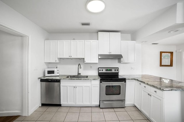 kitchen featuring white cabinets, sink, appliances with stainless steel finishes, light tile patterned flooring, and light stone counters