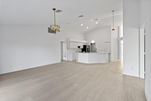 unfurnished living room featuring light wood-type flooring and high vaulted ceiling