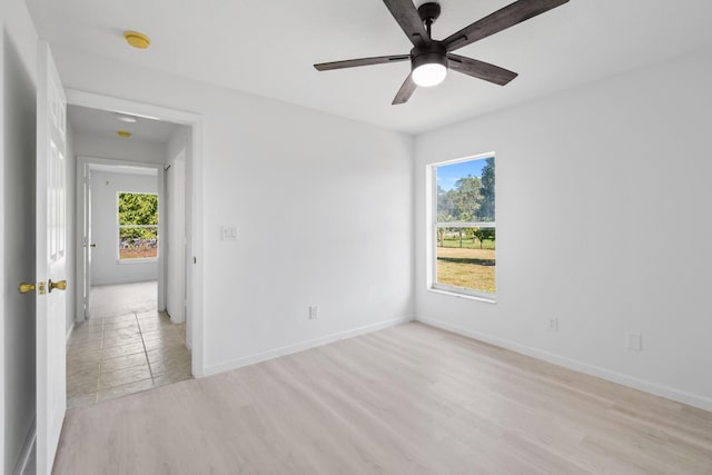 empty room with ceiling fan, light wood-type flooring, and a wealth of natural light