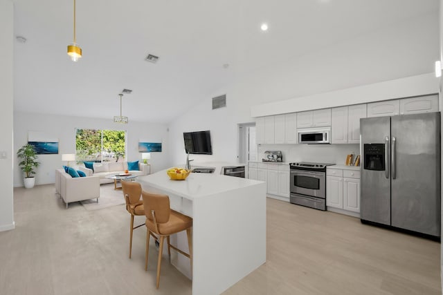 kitchen with a kitchen bar, white cabinetry, pendant lighting, and stainless steel appliances