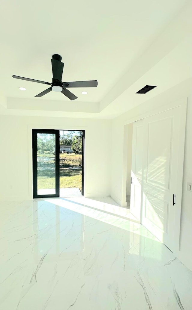 spare room featuring a tray ceiling and ceiling fan