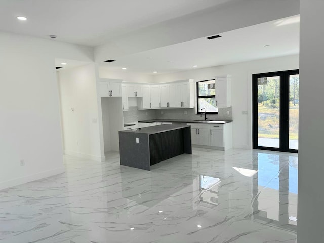 kitchen featuring white cabinetry, sink, french doors, backsplash, and a kitchen island