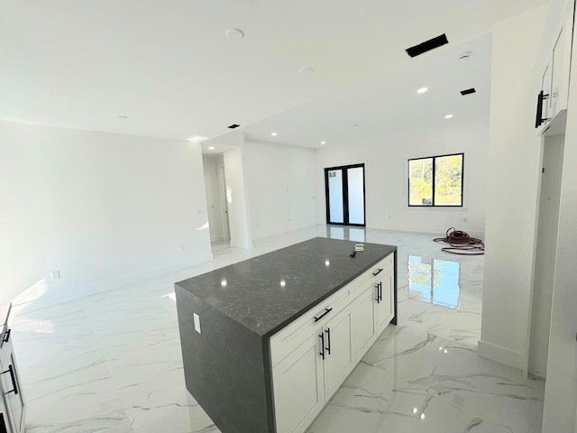 kitchen featuring white cabinets, a kitchen island, and dark stone countertops