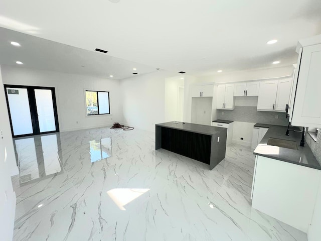 kitchen featuring decorative backsplash, a center island, white cabinets, and sink