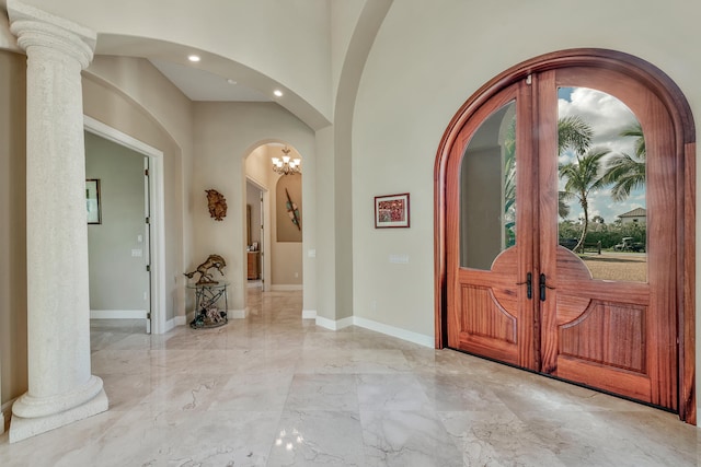 entrance foyer featuring decorative columns, french doors, and a notable chandelier