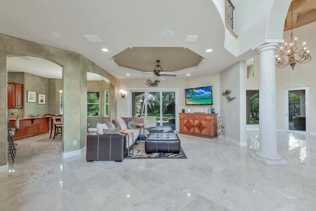 living room featuring ceiling fan with notable chandelier and a tray ceiling