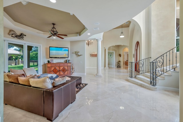 living room with decorative columns, a raised ceiling, and ceiling fan