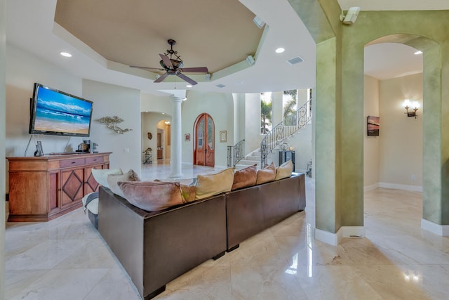 interior space featuring a tray ceiling, ornate columns, and ceiling fan