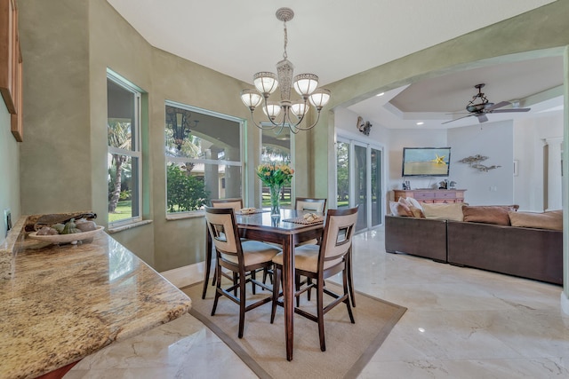 dining space featuring ceiling fan with notable chandelier and a tray ceiling