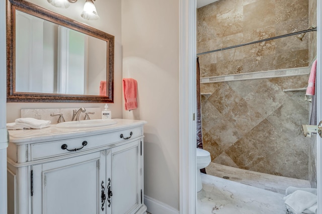 bathroom with vanity, toilet, and tiled shower