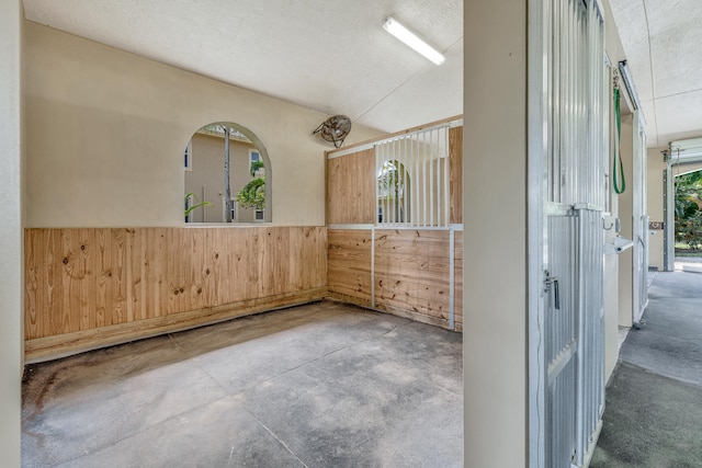 spare room featuring concrete flooring, a textured ceiling, and wood walls