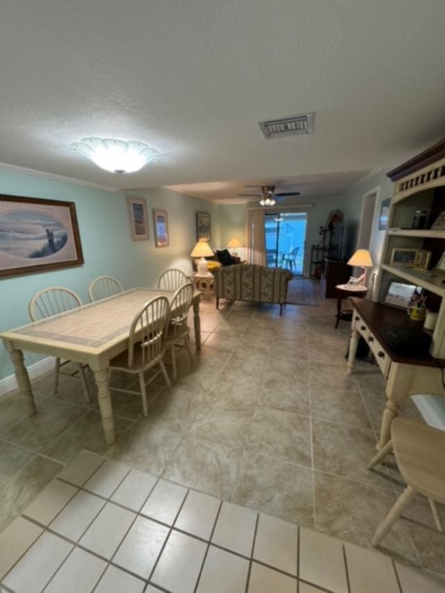 tiled dining room with ceiling fan and ornamental molding