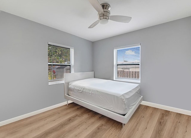 bedroom with multiple windows, ceiling fan, and light hardwood / wood-style flooring