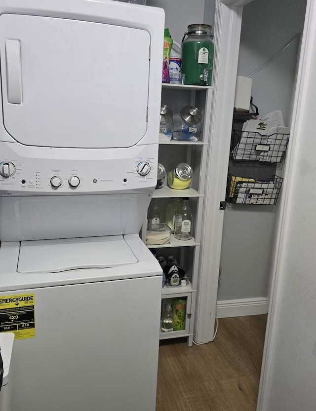 clothes washing area with stacked washing maching and dryer and dark wood-type flooring