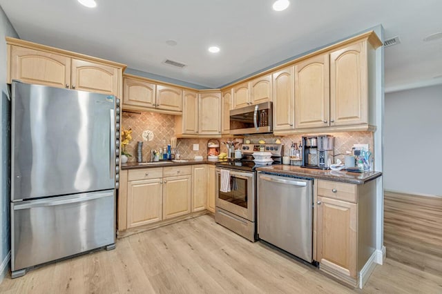 kitchen with backsplash, light wood-type flooring, stainless steel appliances, and light brown cabinetry