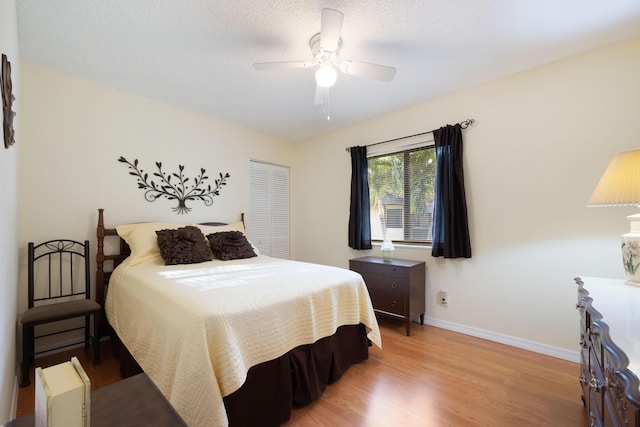 bedroom with a textured ceiling, light wood-type flooring, a closet, and ceiling fan