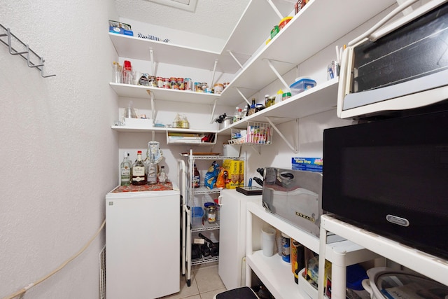 laundry area with light tile patterned floors and a textured ceiling