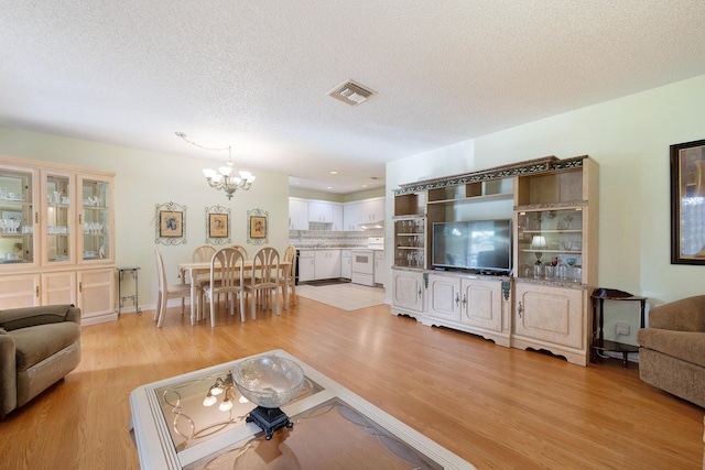 living room featuring a chandelier, a textured ceiling, and light wood-type flooring